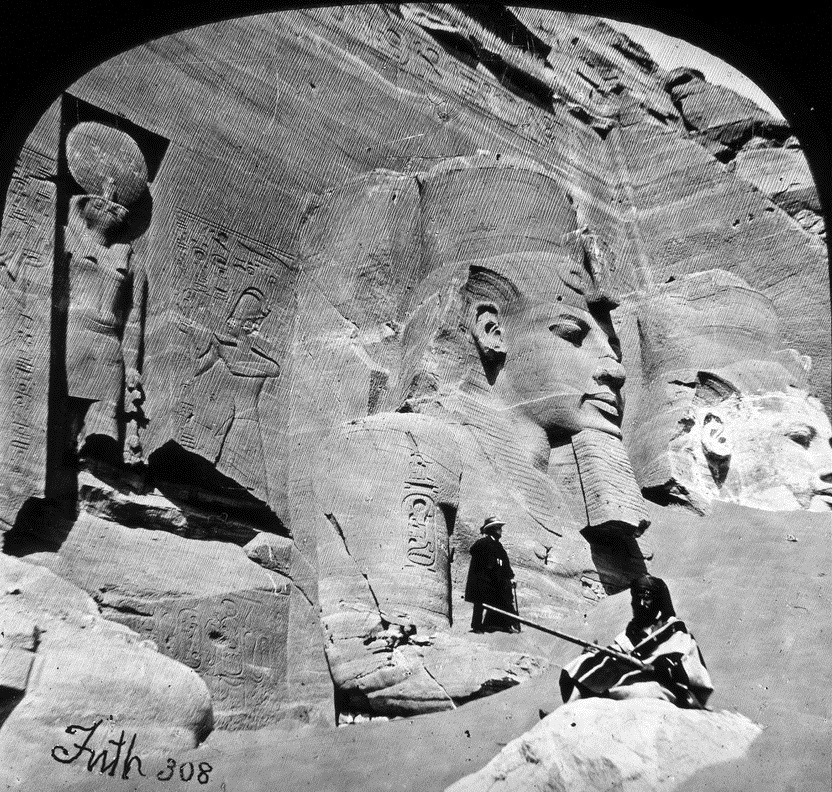 Photo of monument with sand covering half of one figure and all except the face of another
